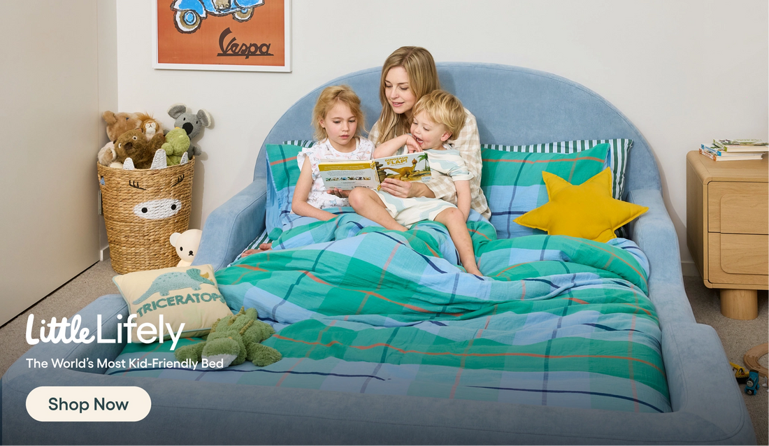 Woman reading to two children on a 'Little Lively' bed with colorful bedding.