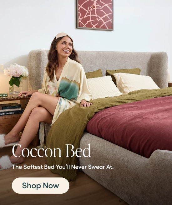 Woman in a robe sitting on a bed with 'Coccon Bed' branding.