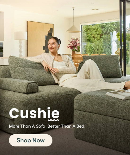Woman sitting on a green 'Cushie' sofa in a modern living room.