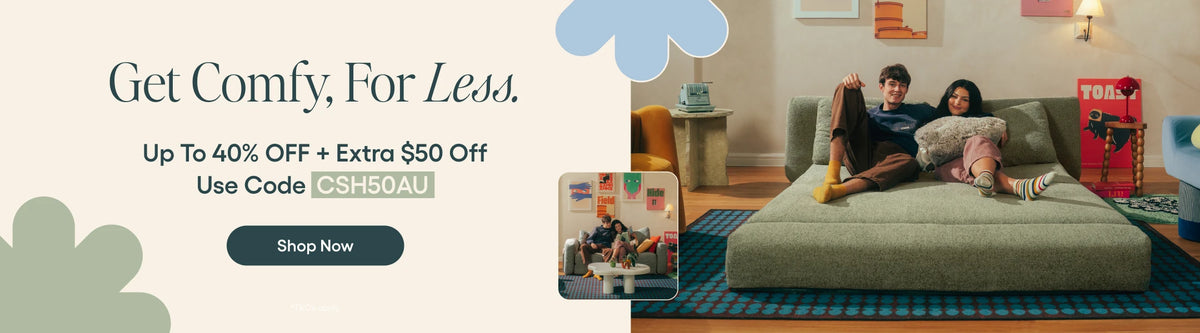 Promotional banner for a sofa listing, showing a woman and man reclining on a light gray upholstered sofa in a living room. Large text on the left reads 'Get Comfy, For Less.