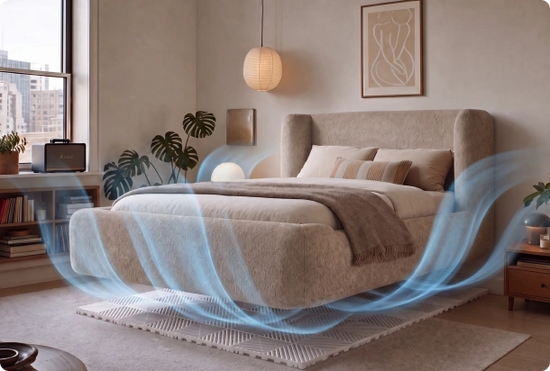 A modern upholstered bed in a softly lit bedroom, with blue airflow graphics suggesting a cooling or air-quality feature. The room includes a window, plants, a hanging lamp, framed wall art, and bedside tables.