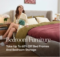 Woman in a robe sitting on a bed with bedding, surrounded by bedroom furniture and storage solutions.