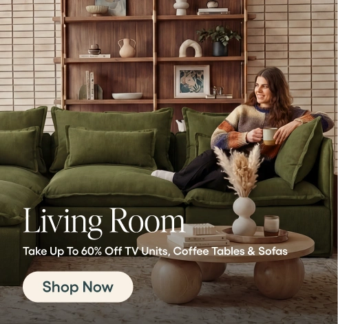 Woman sitting on a green sofa in a living room with a coffee table and shelves in the background.