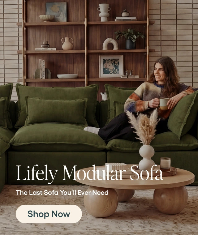 Woman sitting on a green modular sofa with a coffee table and bookshelf in the background.