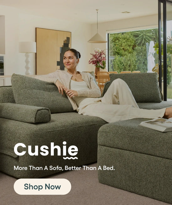Woman sitting on a green 'Cushie' sofa in a living room.