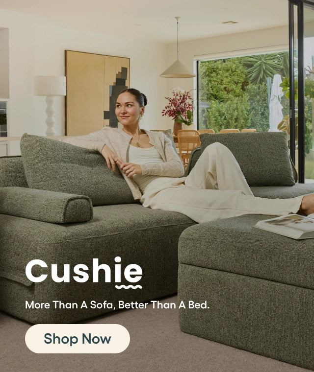 Woman sitting on a green 'Cushie' sofa in a living room.
